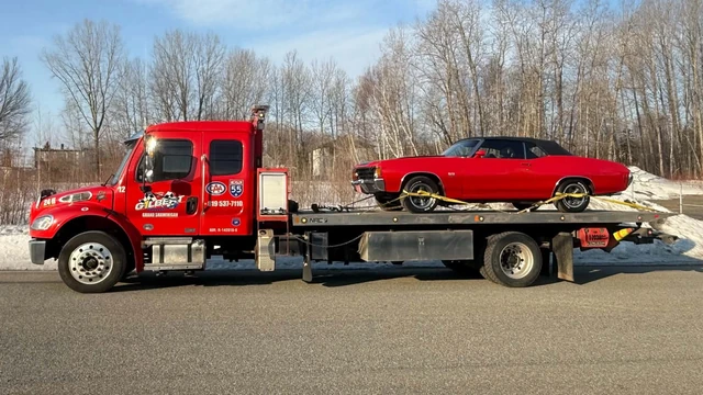 Remorquage sur plateforme : camion-plateau rouge de Remorquage Gilbert, « Grand Shawinigan » et logo CAA sur la portière, transportant une Chevelle décapotable rouge solidement sanglée
